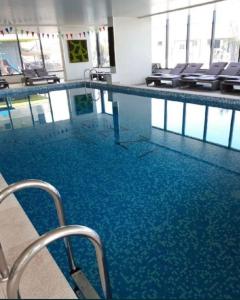 ein großer Pool mit blauem Wasser in einem Gebäude in der Unterkunft Black Sea Studio & Spa & Pools Mamaia Nord in Mamaia Nord – Năvodari