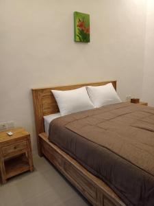 a bedroom with a bed with a wooden frame and a table at Parama Homestay Balangan in Uluwatu