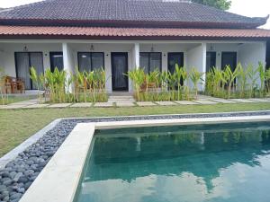 a villa with a swimming pool in front of a house at Parama Homestay Balangan in Uluwatu