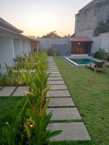 a garden with a stone path leading to a swimming pool at Parama Homestay Balangan in Uluwatu