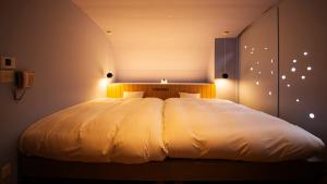 萩市にあるリゾートホテル美萩のベッドルーム(照明付)の大きな白いベッド1台