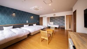una camera d'albergo con due letti e un tavolo di リゾートホテル美萩 a Hagi