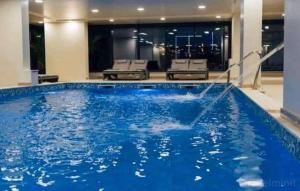 ein großer Pool mit blauem Wasser in einem Gebäude in der Unterkunft Black Sea Studio & Spa & Pools Mamaia Nord in Mamaia Nord – Năvodari