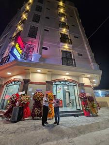 two people standing in front of a building with flowers at LUCKY HOTEL in Vung Tau