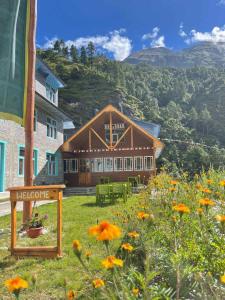 dom z polem kwiatów przed nim w obiekcie Kongde Peak Guest House w mieście Phakding