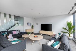Nook Melbourne Apartments في ملبورن: غرفة معيشة مع كنب وتلفزيون بشاشة مسطحة