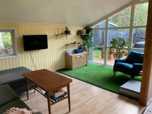 ein Wohnzimmer mit einem Sofa und einem Tisch in der Unterkunft Cosy Summer House Close To Beach, Woods And Town in Fjerritslev