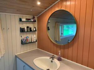 ein Bad mit einem Waschbecken und einem Spiegel in der Unterkunft Cosy Summer House Close To Beach, Woods And Town in Fjerritslev