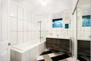 a bathroom with a tub and two sinks and a shower at Airlie Beach Eco Cabins - Adults Only in Airlie Beach