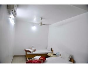 Jyoti Guest House, Bodh Gaya في بود جايا: غرفة بيضاء بسرير وكرسي