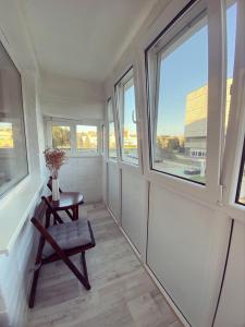 a room with windows and a chair and a table at Erdvus butas su balkonu šalia ežero ir stadiono in Visaginas