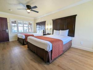 a hotel room with two beds and a ceiling fan at Clarion Collection Wilkie's Inn Pacific Grove - Monterey in Pacific Grove