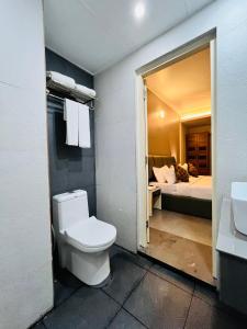 a bathroom with a toilet and a bedroom with a bed at Nexstay Kassaba Inn in Kozhikode