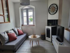 uma sala de estar com um sofá e uma televisão em L'escale des roses em Doué-la-Fontaine
