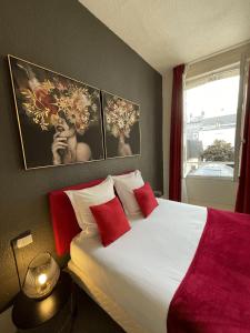 a bedroom with a bed with red pillows and a window at Hotel Le Trouville in Trouville-sur-Mer