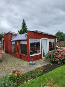 uma casa vermelha com uma janela num quintal em Ferienhaus Katinka em Krummhörn
