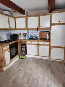 eine Küche mit weißen Schränken und Holzböden in der Unterkunft Ferienhaus Katinka in Krummhörn