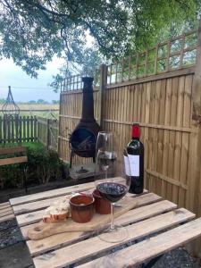 a wooden table with two bottles and a glass of wine at Glen Erin Hut in Gillingham