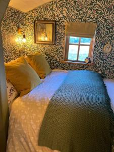 een slaapkamer met een bed met een blauw dekbed en een raam bij Glen Erin Hut in Gillingham