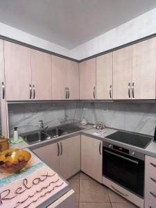 uma cozinha com armários brancos e um lavatório em Maria Apartment em Gjirokastër