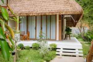 a house with a thatched roof and a bench in front of it at Hue Crown A Luoi Retreat in Ha Tia