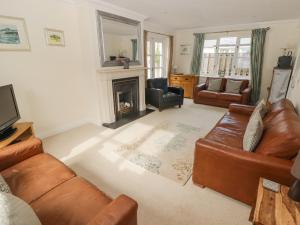 a living room with leather furniture and a fireplace at 3 Strawberry Close in Little Haven