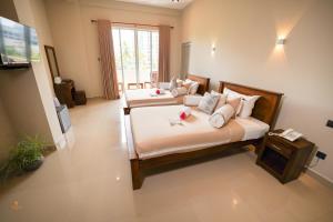 a bedroom with two beds and a television in it at Tharusha Hotel in Galle