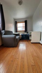 a living room with a couch and a wooden floor at Cozy large room in convenient location near Manhattan by train in Queens