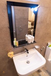 a bathroom with a white sink and a mirror at Tharusha Hotel in Galle