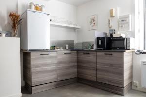 a kitchen with wooden cabinets and a microwave at Charmant studio, au cœur de la ville de Riom in Riom