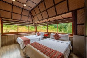 2 camas en una habitación con 2 ventanas en Hue Crown A Luoi Retreat, en Ha Tia