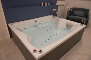 Salerno4Seasons في ساليرنو: حوض استحمام كبير أبيض في غرفة مع كرسي
