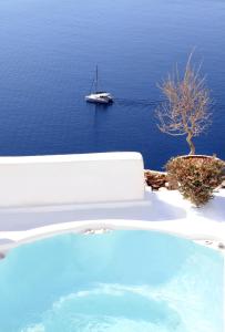 a small boat floating on top of a large body of water at Prime Suites in Oia