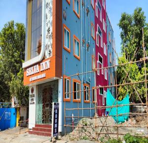 un bâtiment coloré avec un panneau devant lui dans l'établissement Selva Inn, à Pondichéry