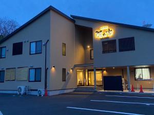 un bâtiment avec un panneau de néon sur son côté dans l'établissement NARITA HOTEL KAKUREGA - Vacation STAY 72264v, à Narita