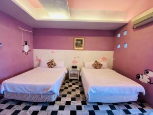 2 camas en una habitación con paredes moradas en Lazy Sheeps Hostel, en Hengchun
