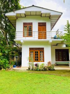 a house with a green lawn in front of it at Summer Ridge - Homestay in Ratnapura