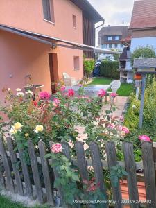 une clôture en bois avec des fleurs devant une maison dans l'établissement BnB LES OISEAUX, chez Claude et Lidia, 26 à 44m2, 2ème étage, à Vendlincourt