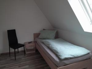 een kleine slaapkamer met een bed en een stoel bij Monteurhaus in Sallgast