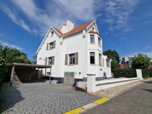 een wit huis met een rood dak op een straat bij Villa Dageraad in De Panne