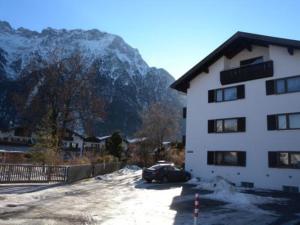 un bâtiment avec une voiture garée à côté d'une montagne enneigée dans l'établissement Rustico -301-, à Mittenwald