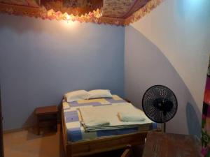KONE-METTLER GUEST HOUSE في Abémé: غرفة نوم بسرير ومروحة في الغرفة