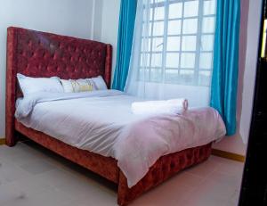 a bed with a red headboard and a window at Urban Elegance in Nairobi