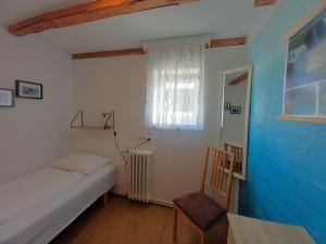 a bedroom with a bed and a chair and a window at Húsavík Green Hostel in Húsavík