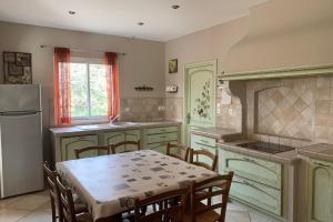 a kitchen with a table and chairs and a refrigerator at LAcacia in Plaissan