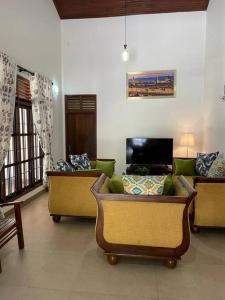Villa Verde Alawwa في Alawwa: غرفة معيشة بها ثلاث كنب وتلفزيون