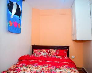 Schlafzimmer mit einem Bett mit einer roten Bettdecke in der Unterkunft Bosslady staycation A4 in Muchatha
