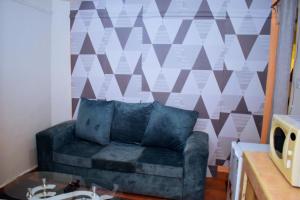 eine Couch in einem Wohnzimmer mit einer geometrischen Wand in der Unterkunft Bosslady staycation A4 in Muchatha