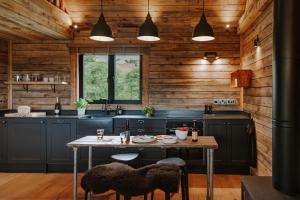 a kitchen with a table and chairs in a kitchen with wooden walls at Woolly Wood Cabins - Bryn in Llandrindod Wells