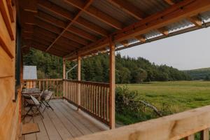 a wooden deck with a table and chairs on it at Woolly Wood Cabins - Bryn in Llandrindod Wells